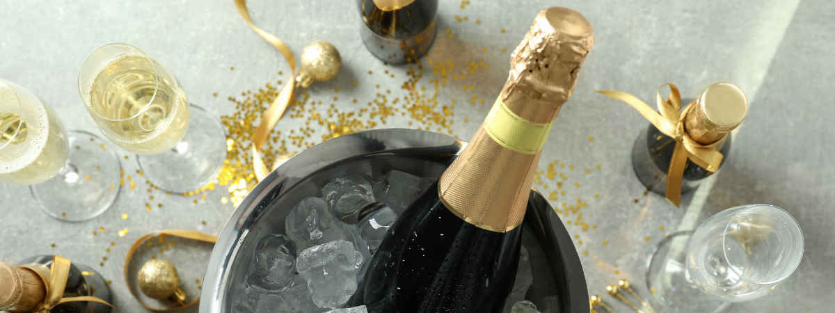 Secchiello porta ghiaccio con bottiglia di champagne al suo interno e bicchieri a lato